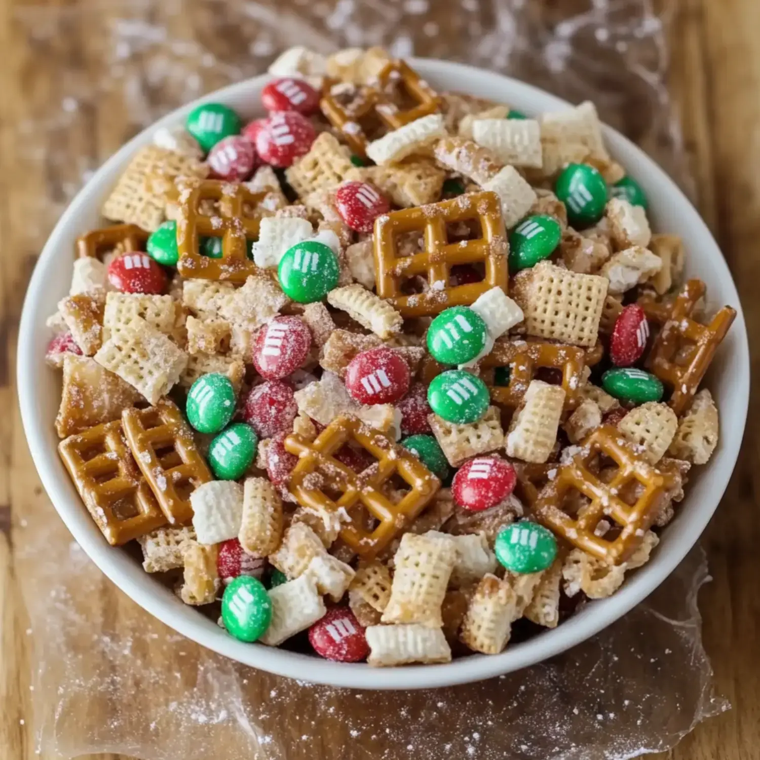 Un primer plano de un bol lleno de una mezcla colorida de cereales, pretzels y chocolatinas rojas y verdes.