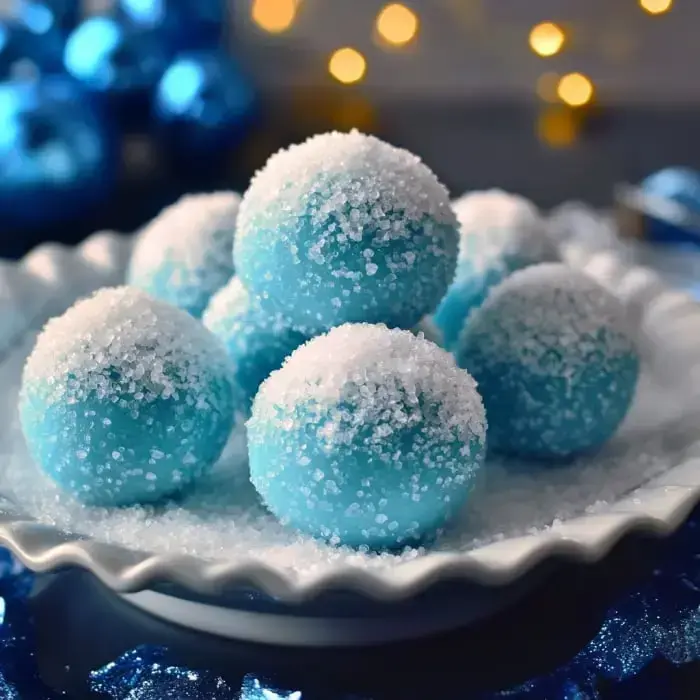 Un plato de esferas azules cubiertas de azúcar granulado colocado en un entorno festivo con adornos azules e iluminación suave.