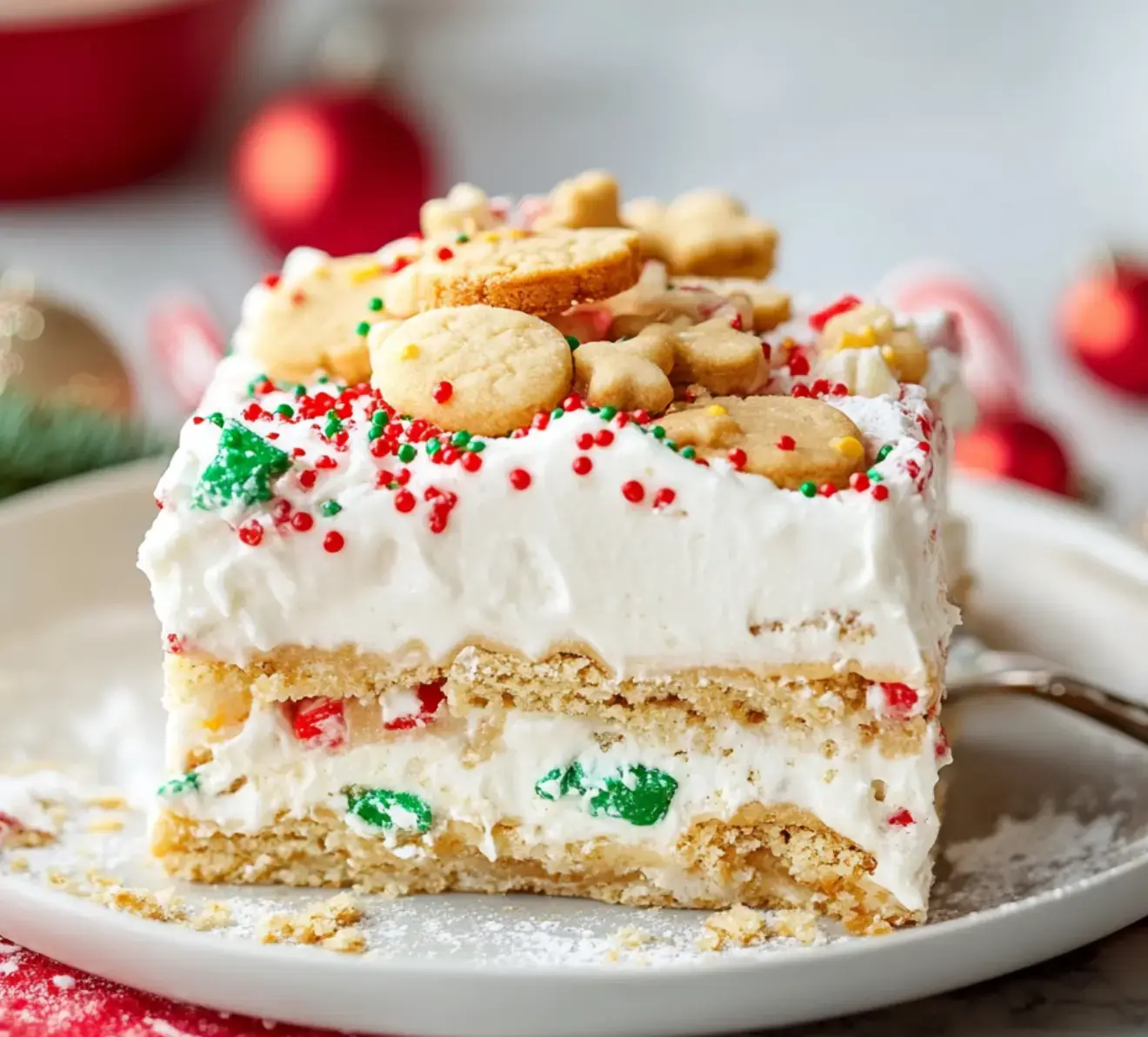 Un postre navideño decorado con capas de crema, fideos de colores y galletas festivas en forma de estrella encima servido en un plato.